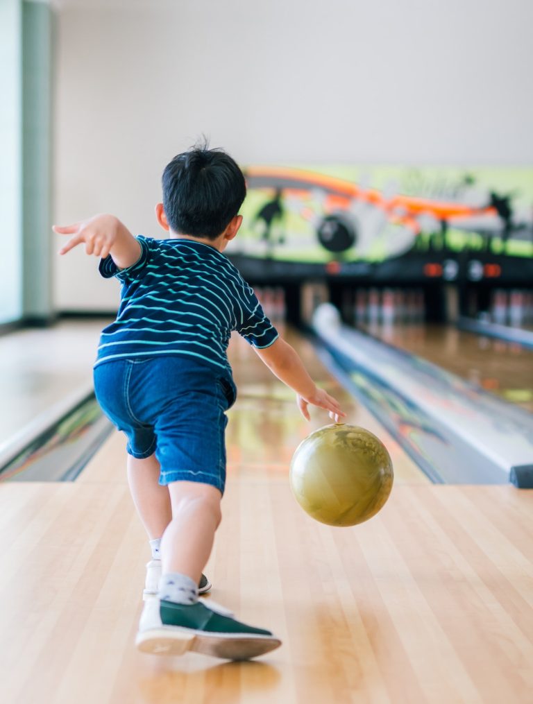 Back view child throwing bowling ball