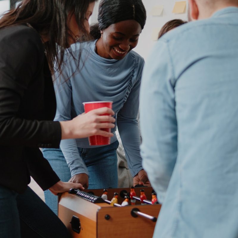 Group of colleagues playing at foosball table after work